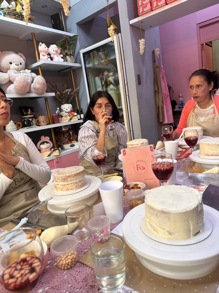 Mujeres conversando alrededor de una mesa con tortas y copas de sangría