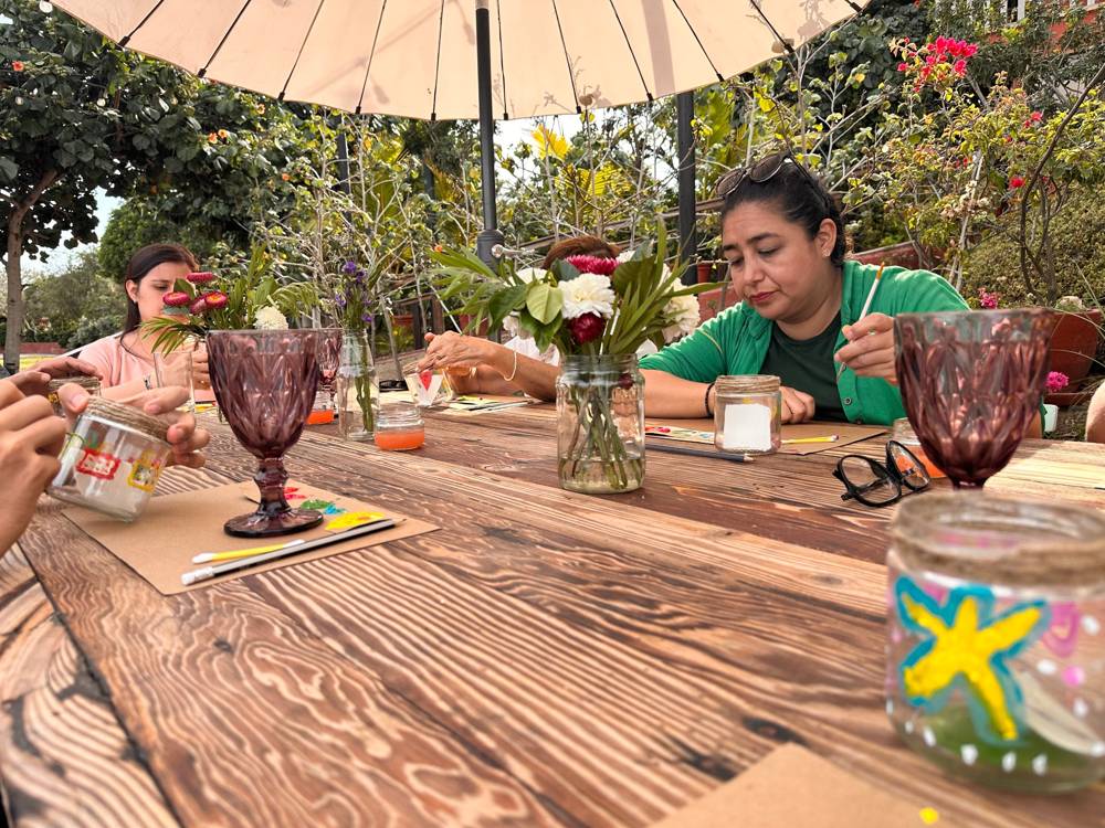Mujeres pintando frascos en un jardín
